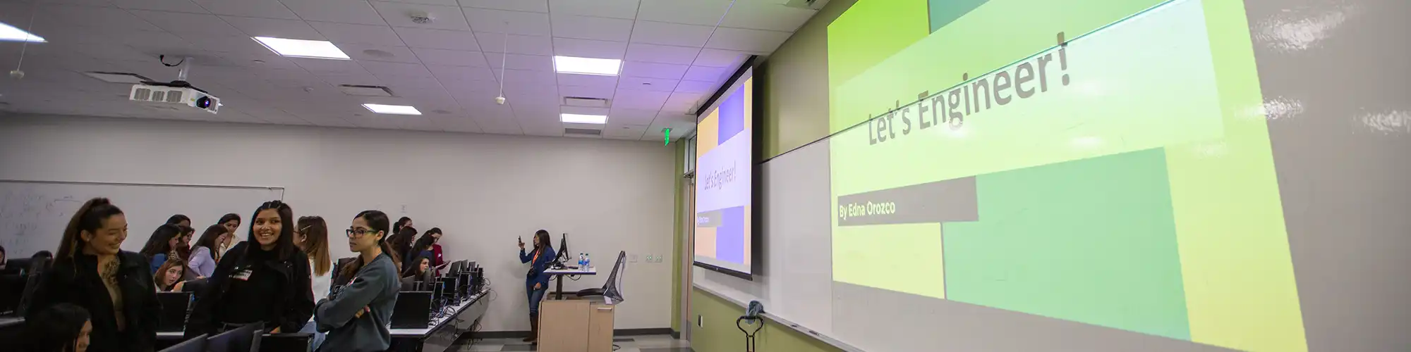 Students at a presentation with a screen display the words Let's Engineer!