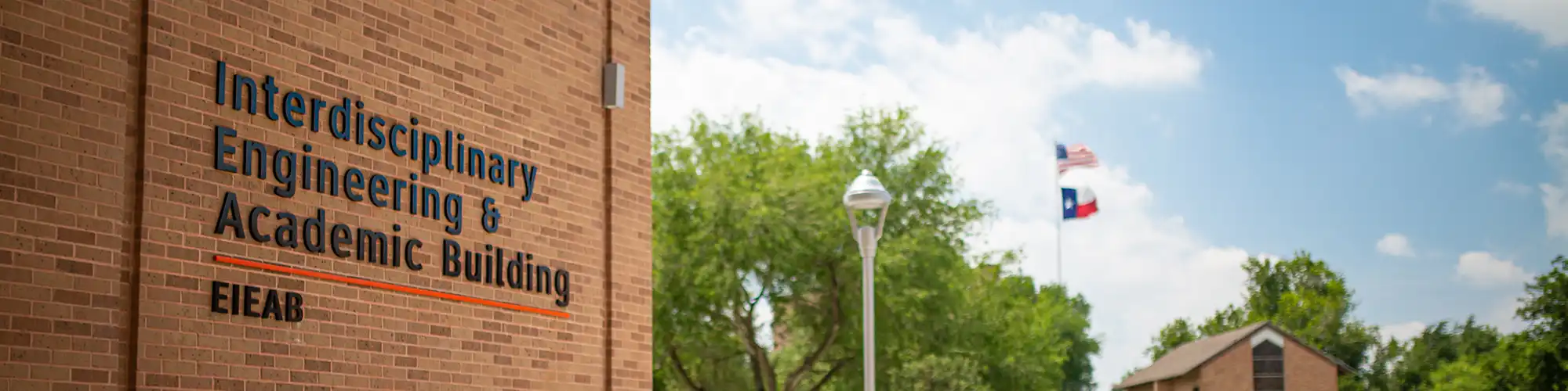Entrance of engineering building with flags waving in the background.