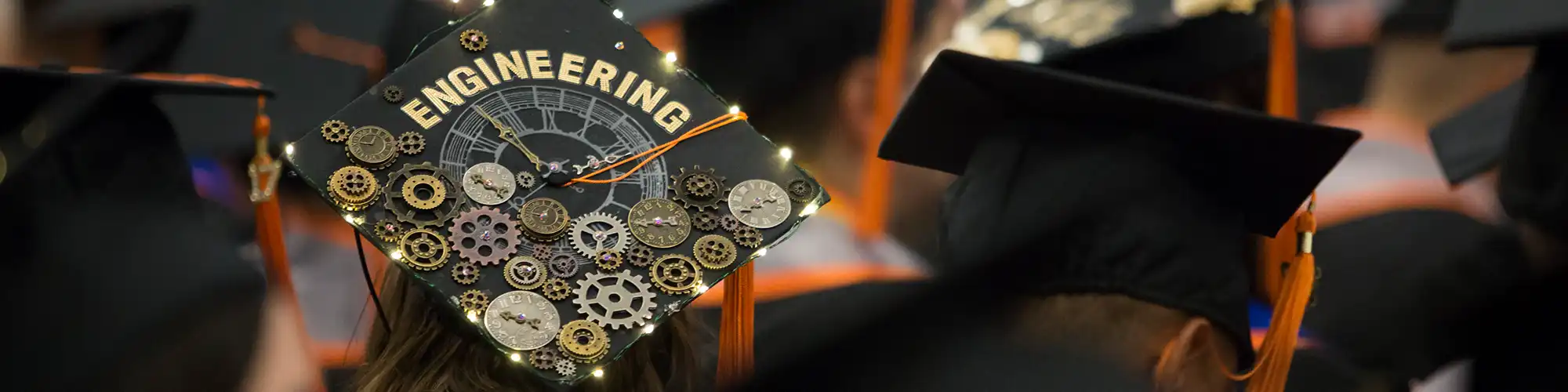 Photo of graduation cap decorated with gears and the word engineering.