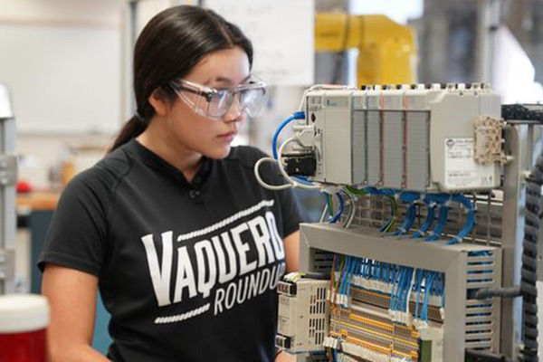 Student wearing safety goggles using equipment.