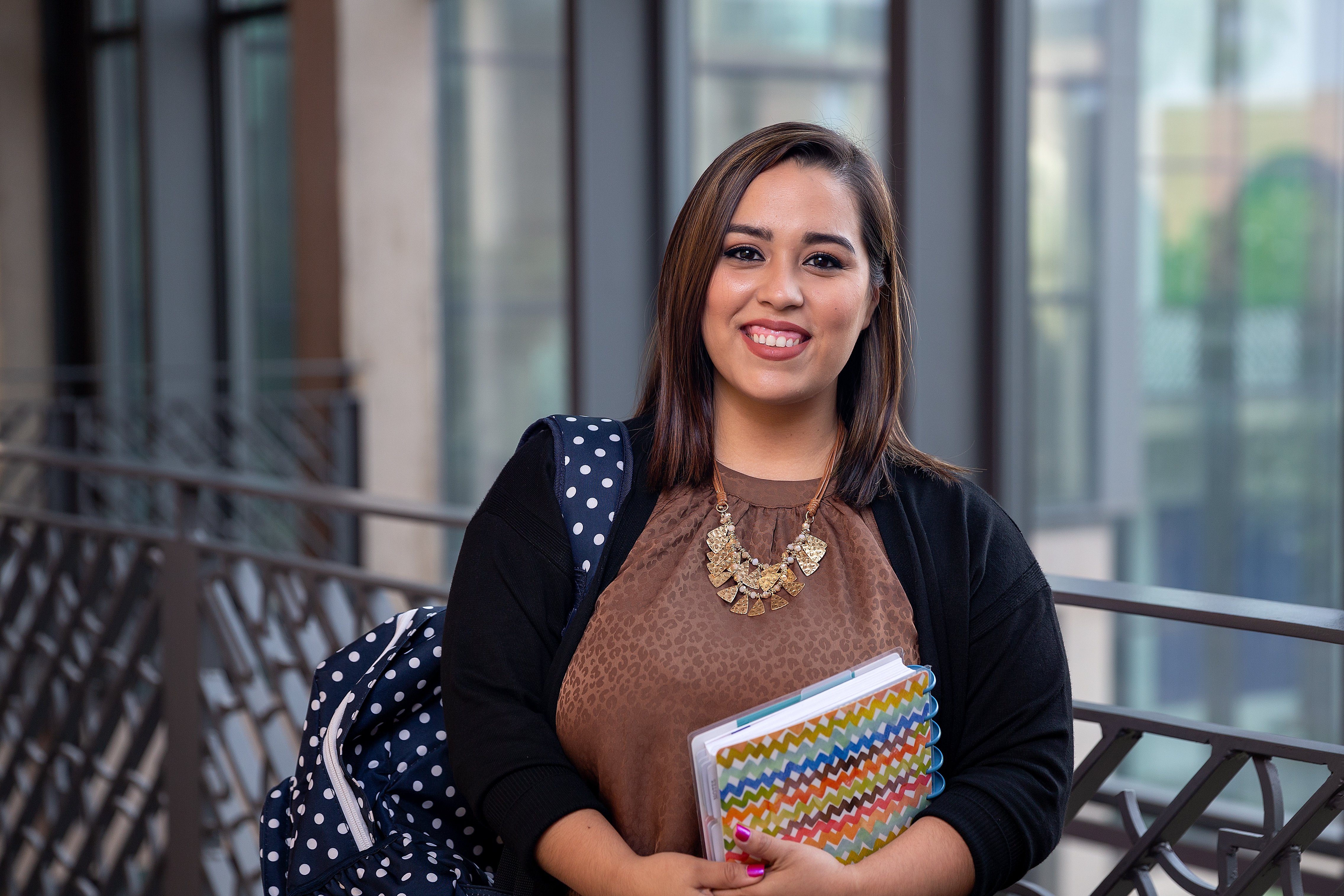 CEP student holding books and smiling to the camera.