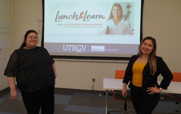 Employees stand in front of a projection screen with the Lunch & Learn branding displayed.