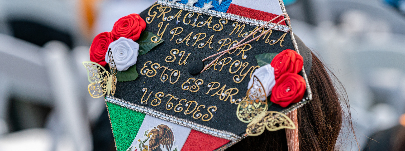 A student uses her graduation cap to thank her parents in Spanish
