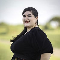 Smiling, staff portrait with blurred, outdoor background.