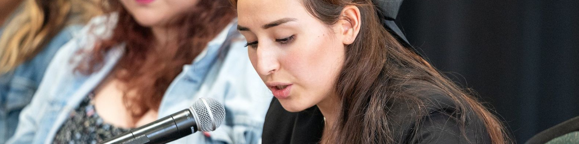 Student reading off paper into mic during event.