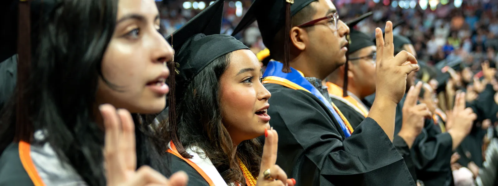graduates showing their V's Up at commencement. 