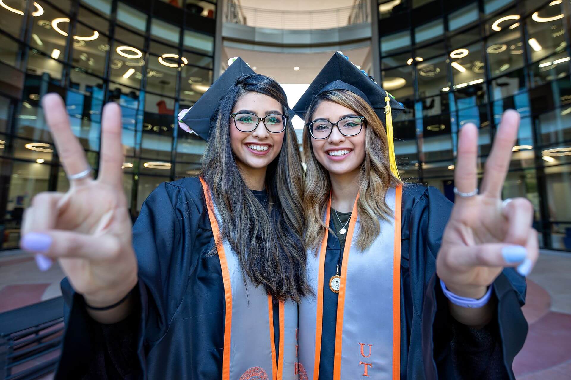 two graduating students showing v's up in the college of science building