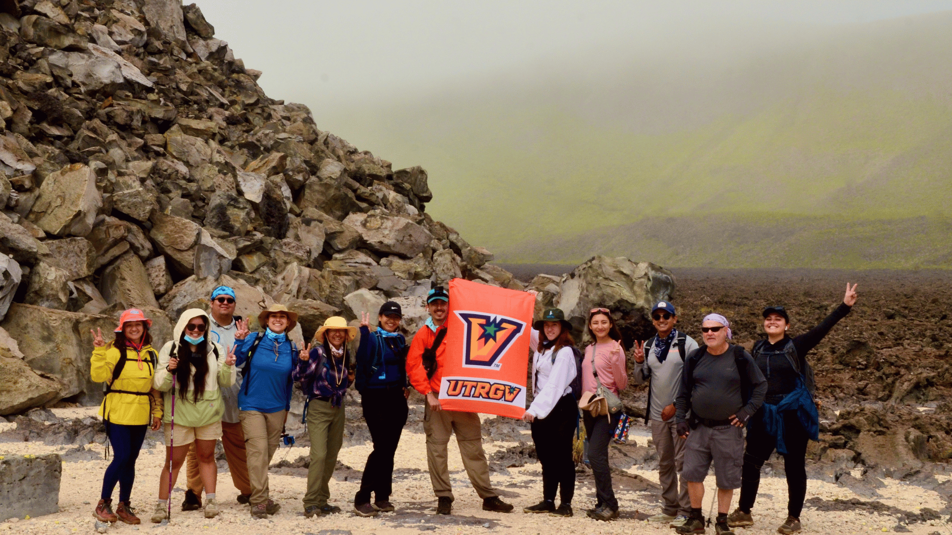 Students posing in a group photo around volcanic rock at Galapagps Islands