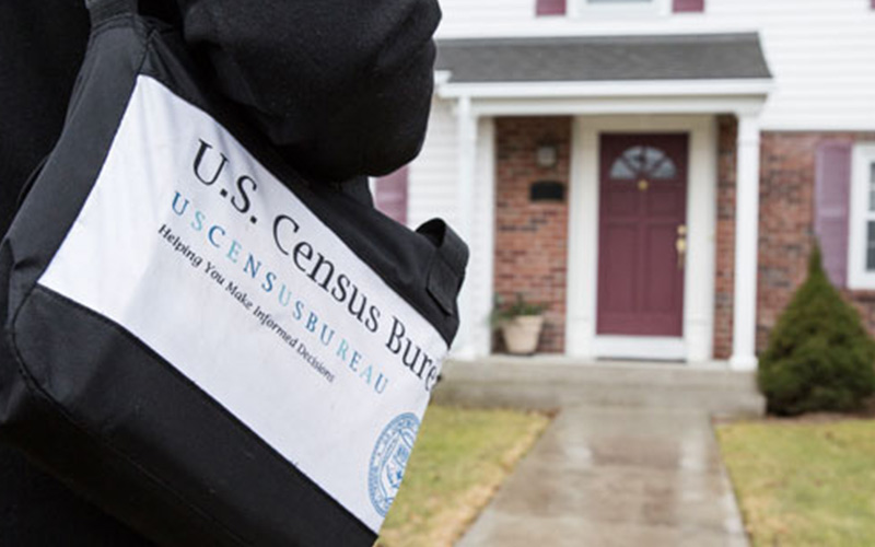 Mailman holding a US Census Flyer on their bag