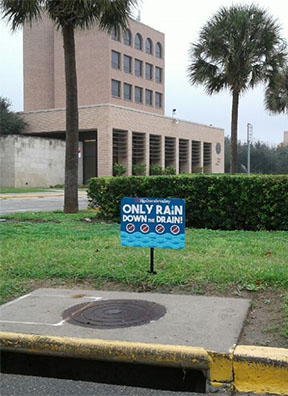 Only Rain Down The Drain! sign next to one of the UTRGV sewers.