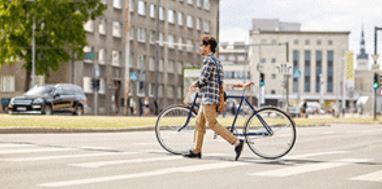 Bicyclist walking with bicycle while walking through the crosswalk.