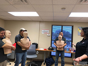 The class practices abdominal thrusts as part of the first aid skills check for choking adults and children.