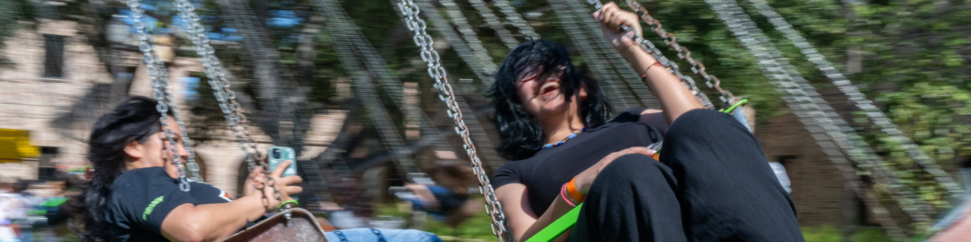 Two students sitting and flying in the air on a carnival ride.