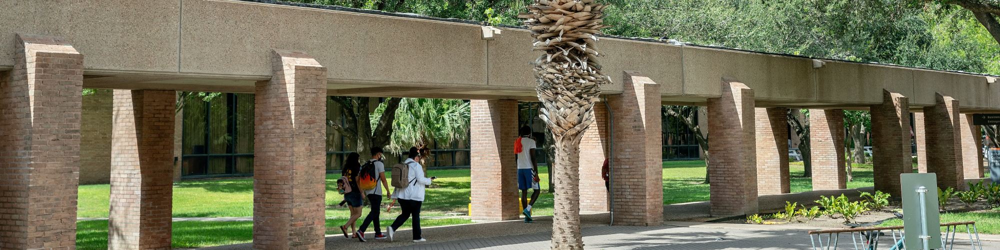 Students walking outside on campus covered walkway.