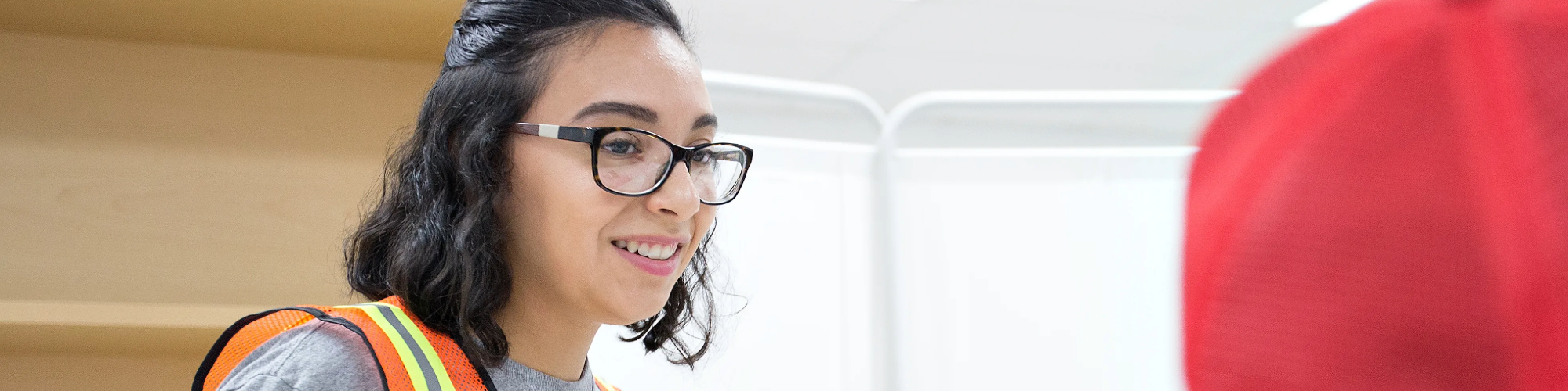 Student in an orange vest talking to someone.