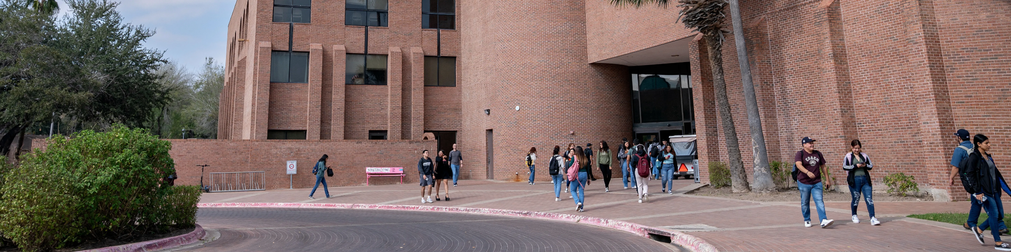Distant shot of students walking outside of a building on campus.
