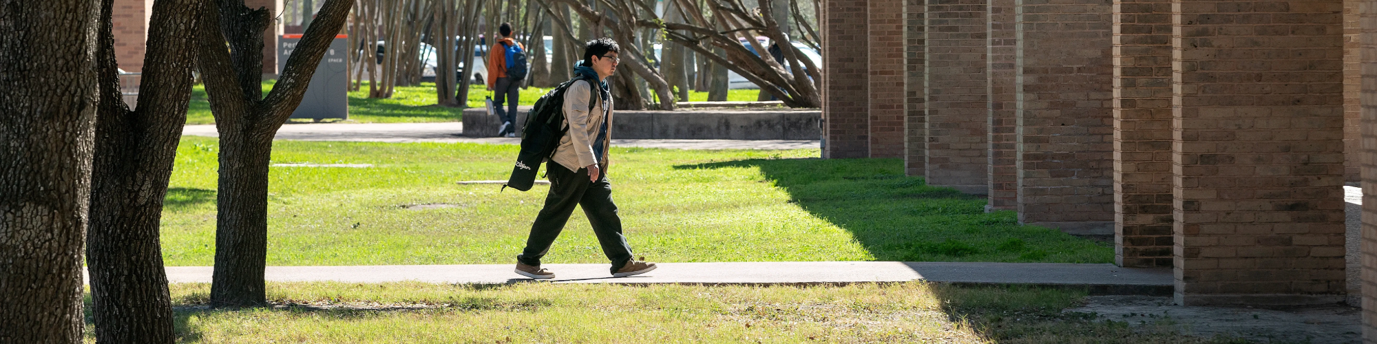 Student walking across campus with backpack and jacket on.
