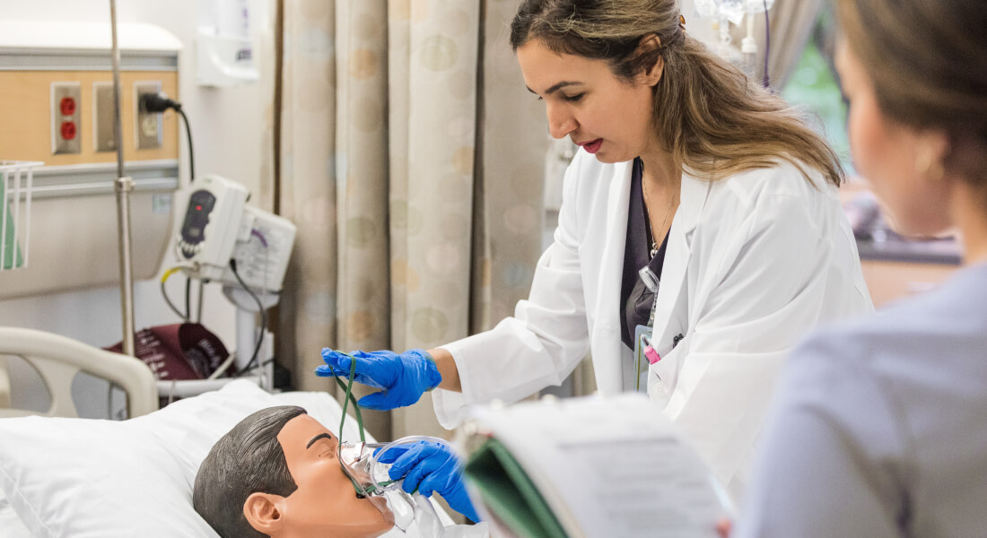 Clinician demonstrates airway management on a medical training mannequin in a hospital simulation setting.