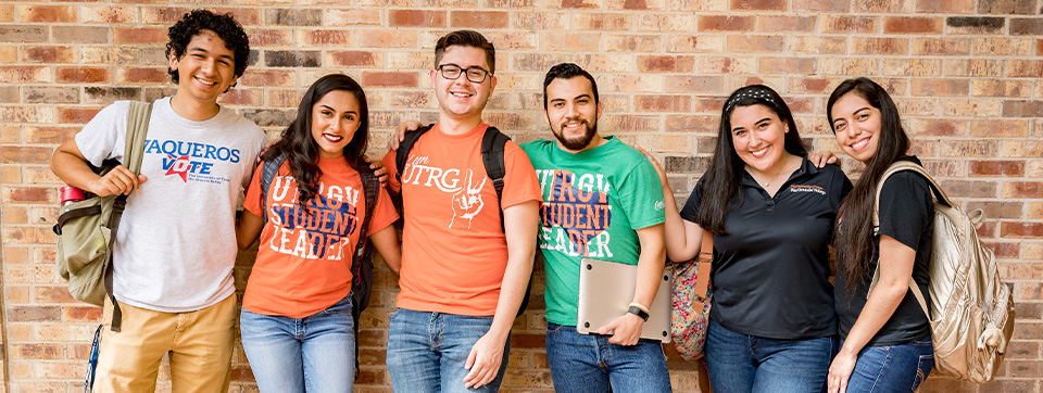 Group of students posing in front of a brick wall.