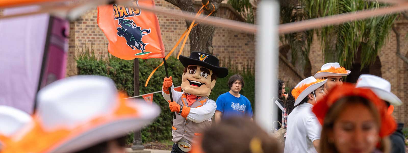 Vaquero mascot rasing the flag.
