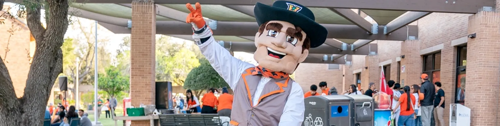Vaquero mascot riding a tricycle