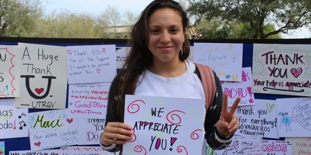 Happy female student holding thank you sign