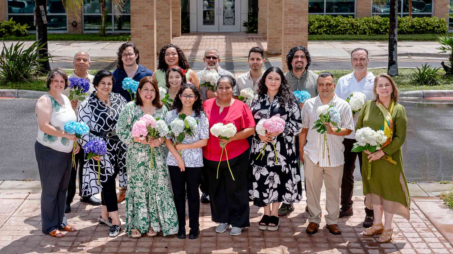 Research team gathers outdoors with flowers, celebrating collaboration and community commitment to Alzheimer's research.