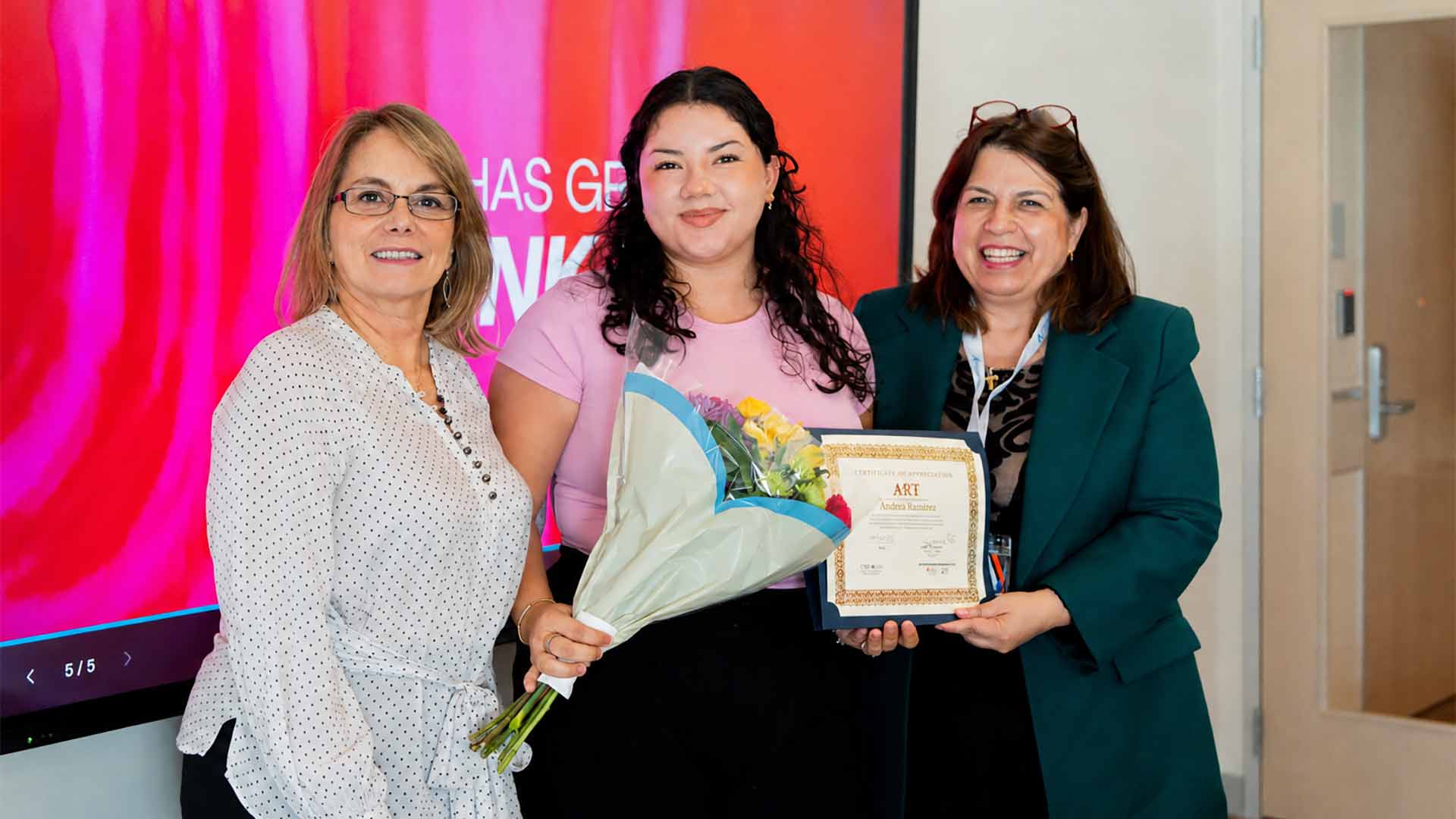Student researcher receives a certificate and flowers in recognition of her achievements in a research program.