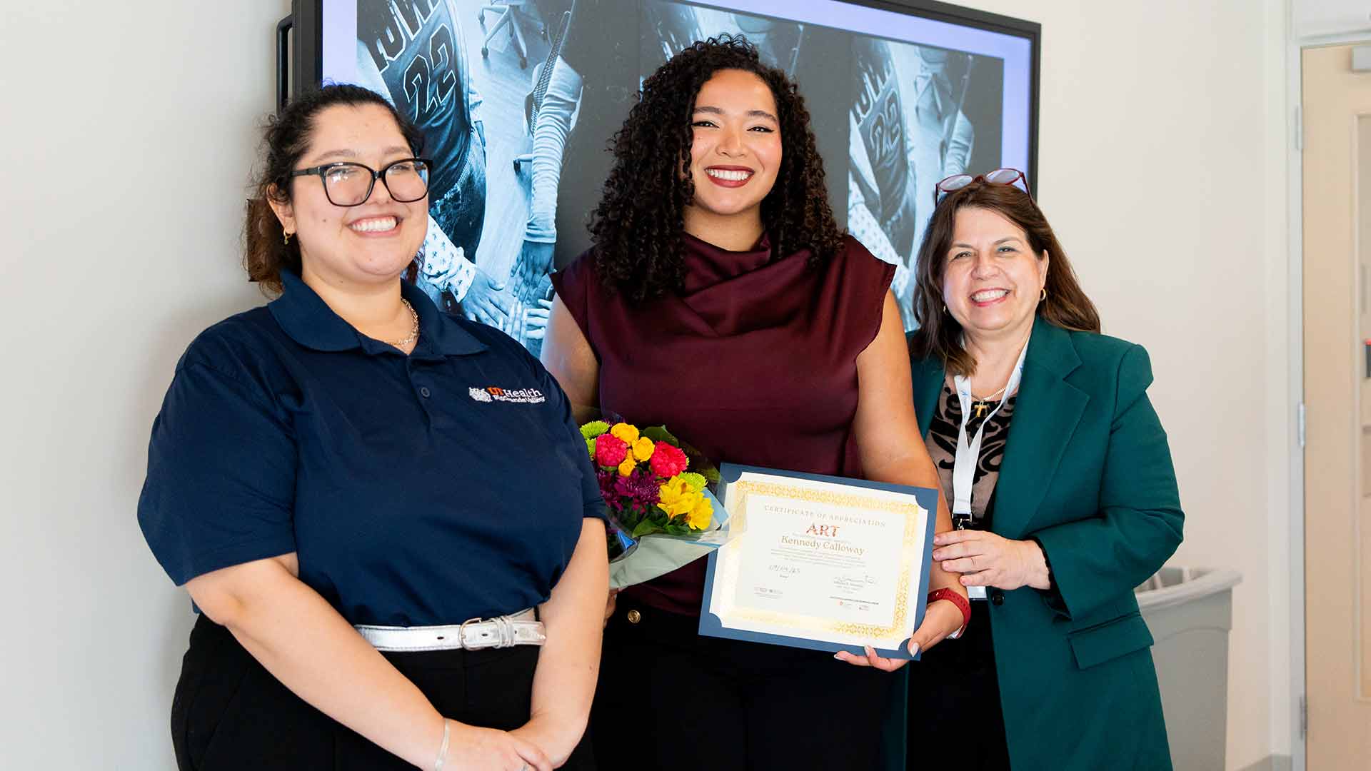 Student researcher receives a certificate and flowers in recognition of her achievements in a research program.
