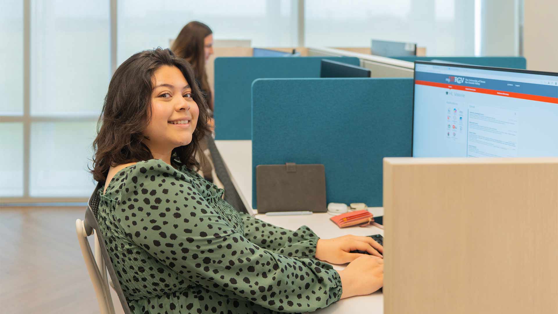 Student researcher works at a computer in a shared office, gaining hands-on experience through a research program.
