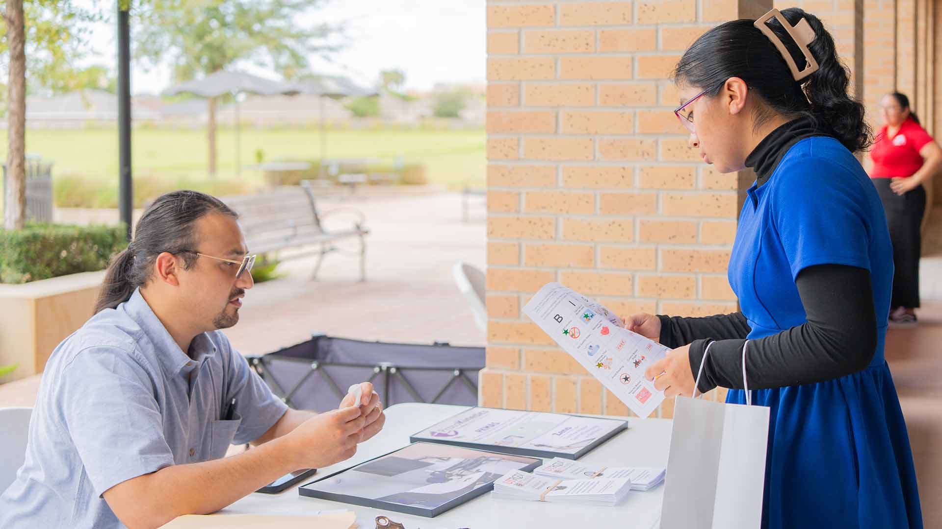 Community member receives health education materials during an outreach event promoting wellness and research participation.