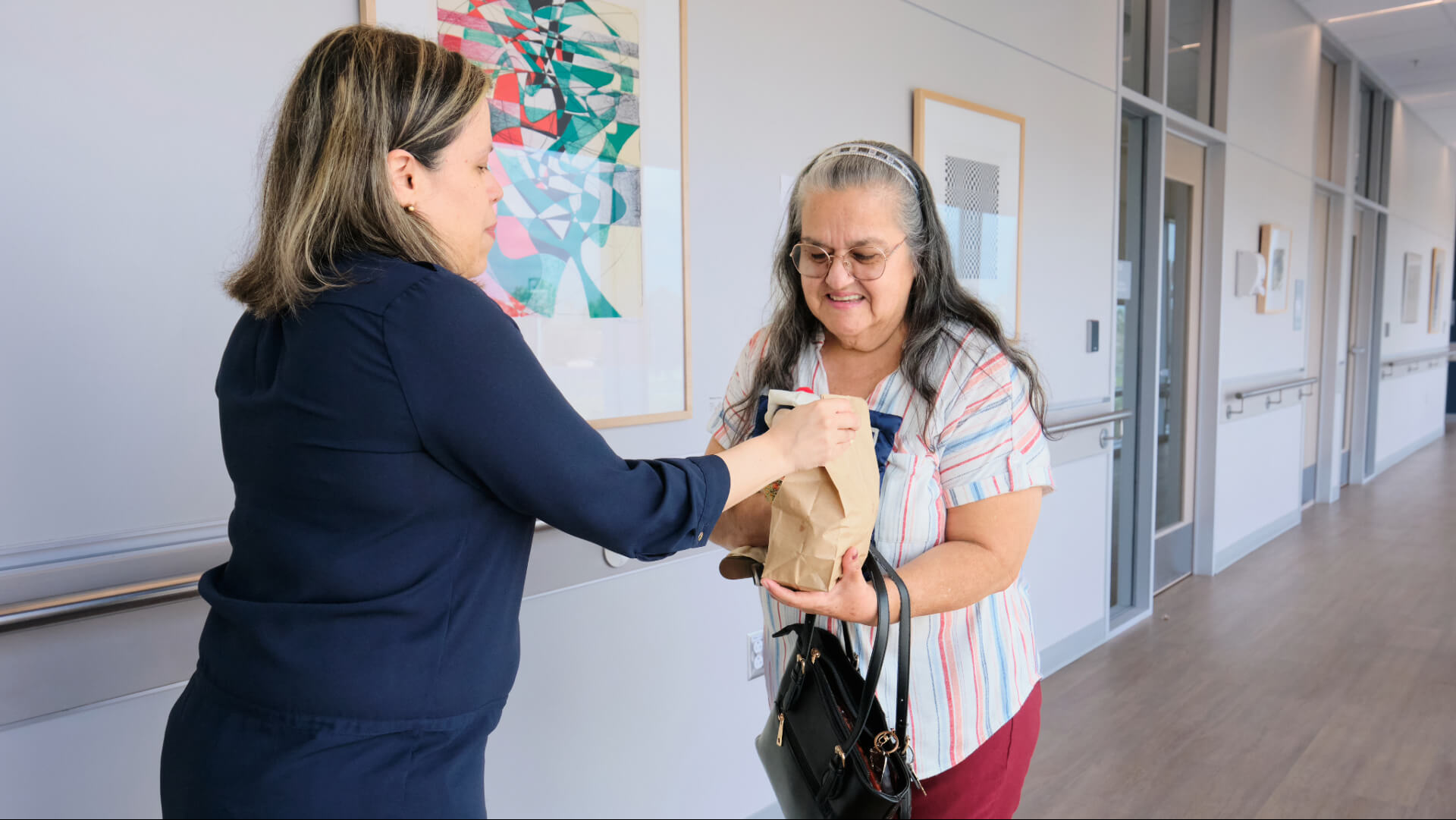 Research participant and healthcare provider smile together while holding a memory assessment doll during a clinic visit.