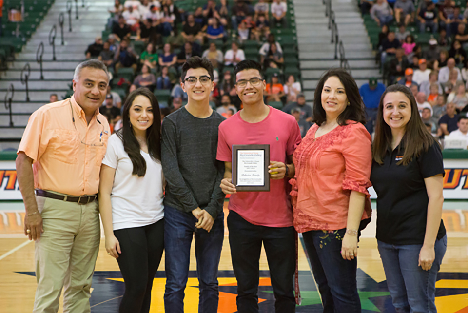 UTRGV sophomore Luis Cano (center, with plaque), who is pursuing a degree in electrical engineering, is the winner of the 2018 UTRGV Family of the Year essay contest. Cano wrote that when he was very young, he was taken away from his birth parents and lived in foster homes until his aunt and uncle fought to gain custody of him and won. The family was recognized Feb. 24, 2018, during a UTRGV Men’s Basketball game at the Fieldhouse on the Edinburg Campus, as part of the university’s Family Weekend. Shown here from left are Cano’s adoptive father Alex Palacios, Alyssa Palacios, Aaron Palacios, Cano, his adoptive mother Dalinda Palacios, and Jodie Dominguez, assistant director for mentoring and transition services in the UTRGV Office of Student Involvement. (UTRGV Photo by Silver Salas)
