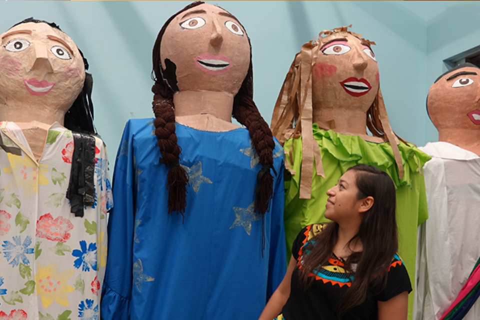 Lucero Rodriguez, president of the UTRGV Latino Theatre Initiatives, stands on a chair to pose with the UTRGV mojigangas, enormous puppets the student organization made this spring. The group is including the 11-foot-tall puppets in a play they’ll be performing in October in Brownsville and Edinburg. In the play, a girl’s homemade dolls come to life. (UTRGV Photo by Maria Elena Hernandez)