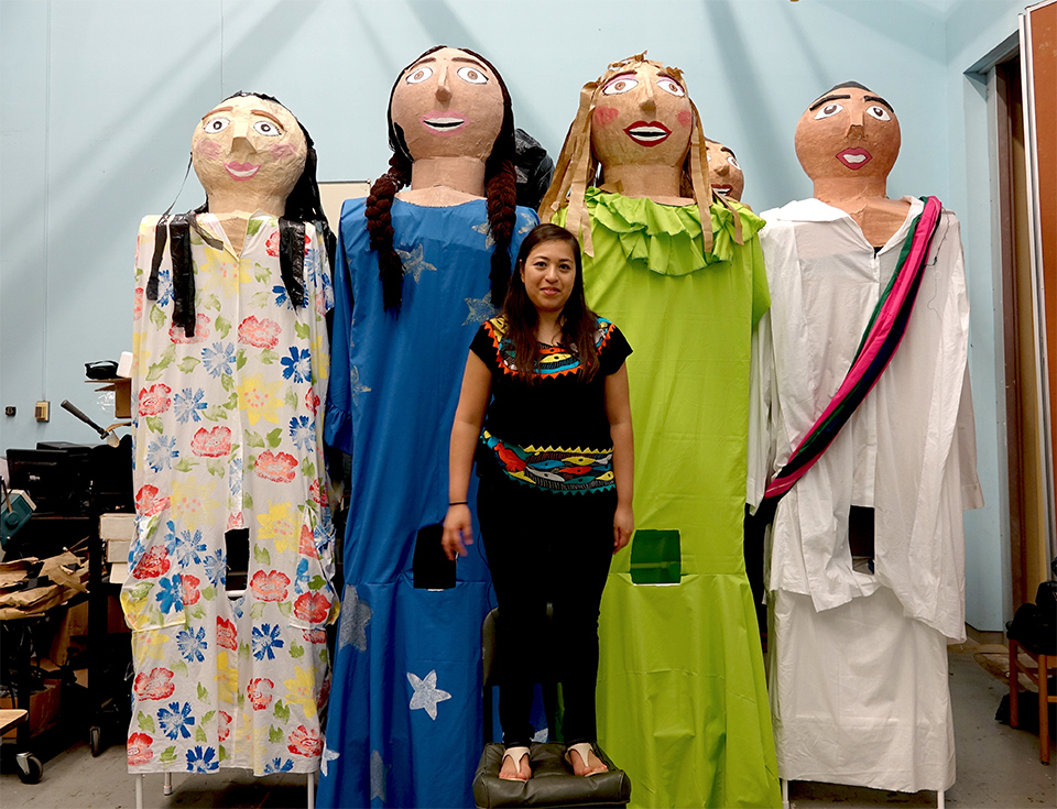 Lucero Rodriguez, president of the UTRGV Latino Theatre Initiatives, stands on a chair to pose with the UTRGV mojigangas, enormous puppets the student organization made this spring. The group is including the 11-foot-tall puppets in a play they’ll be performing in October in Brownsville and Edinburg. In the play, a girl’s homemade dolls come to life. (UTRGV Photo by Maria Elena Hernandez)