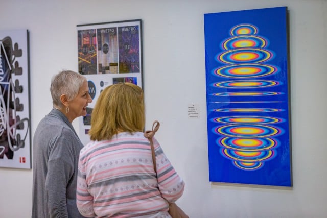 Women look at art exhibit.