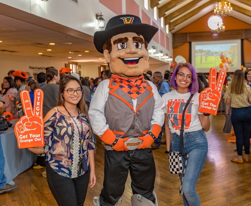 Vaquero Mascot posing for photograph with UTRGV students.