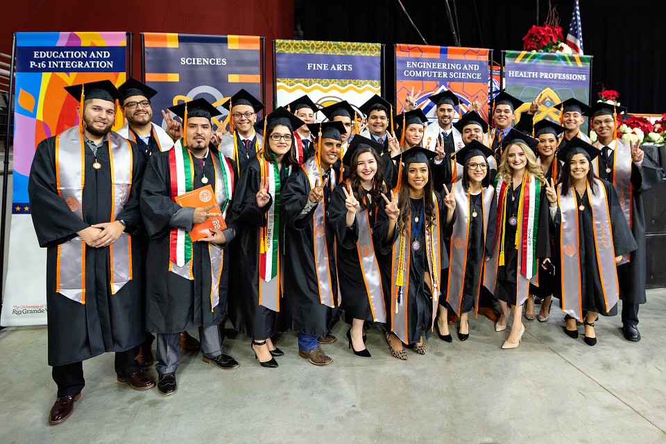 UTRGV graduates posing for photo by college gonfalons