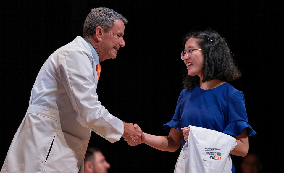 The UTRGV School of Medicine welcomed the Class of 2025 with a White Coat Ceremony on Saturday, July 24, in Edinburg. The ceremony is an important first step in the career of a future physician, serving as a rite of passage at medical schools around the country. Pictured is Dr. Michael B. Hocker, the new dean of the UTRGV School of Medicine, presenting a student with her white coat. (UTRGV Photo by Paul Chouy)