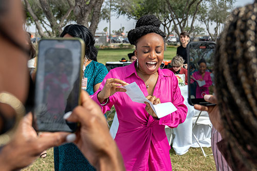 student in punk outfit, excited shows a letter to other peers recording with phones