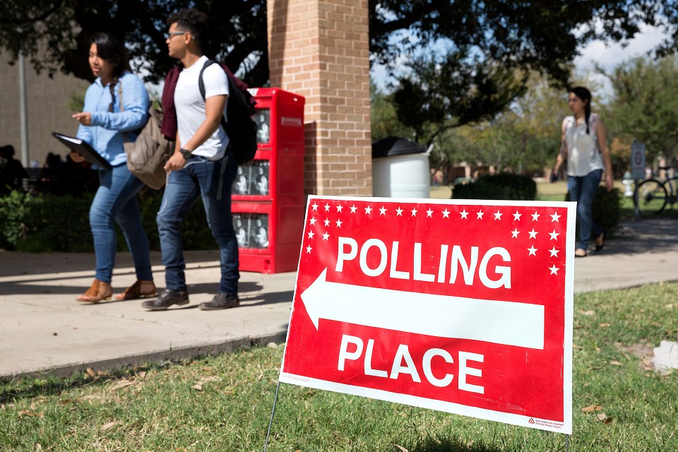 Polling place sign, students walking in background