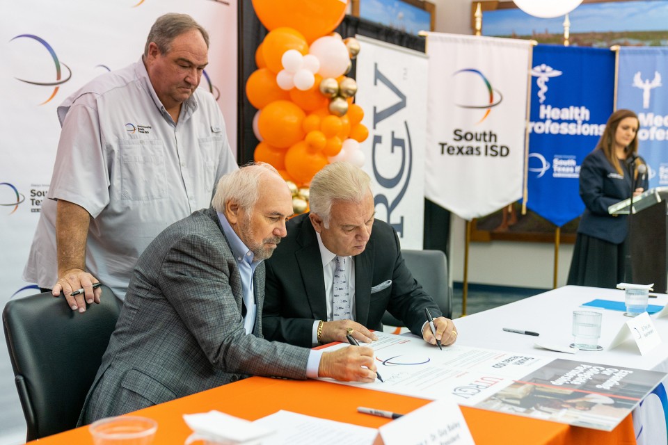 UTRGV President Guy Bailey and Dr. Marco Antonio Lara Jr., South Texas ISD superintendent, sign an agreement in Mercedes on Monday morning to improve dual credit offerings for high school students who plan to attend UTRGV. Standing is Doug Buchanan, STISD board president, who waits his turn to sign the pledge.