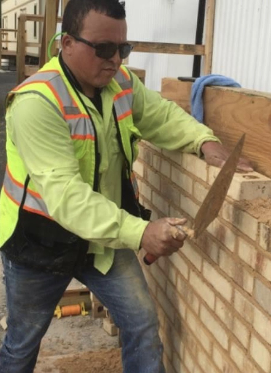 Limon carefully laying brick during a masonry project.