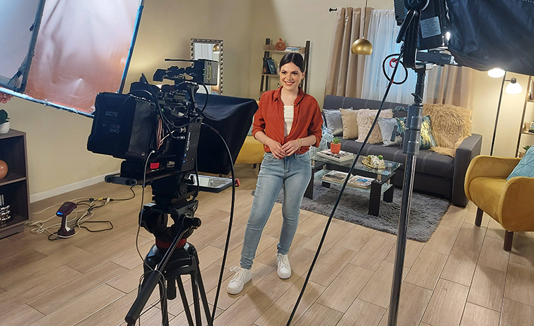 A person stands on a studio set between professional ...