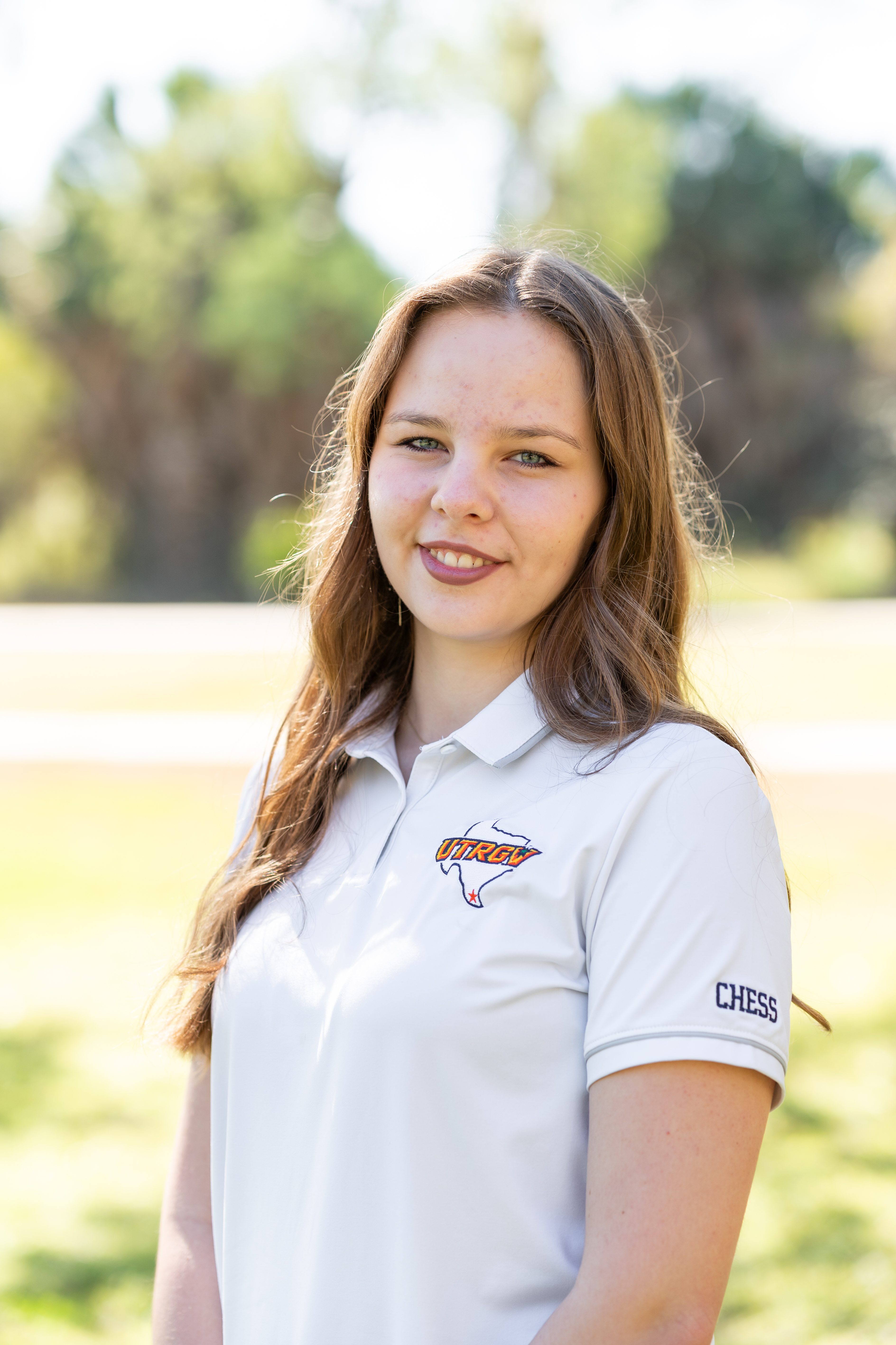 Woman wearing a white polo chess shirt standing outdoors