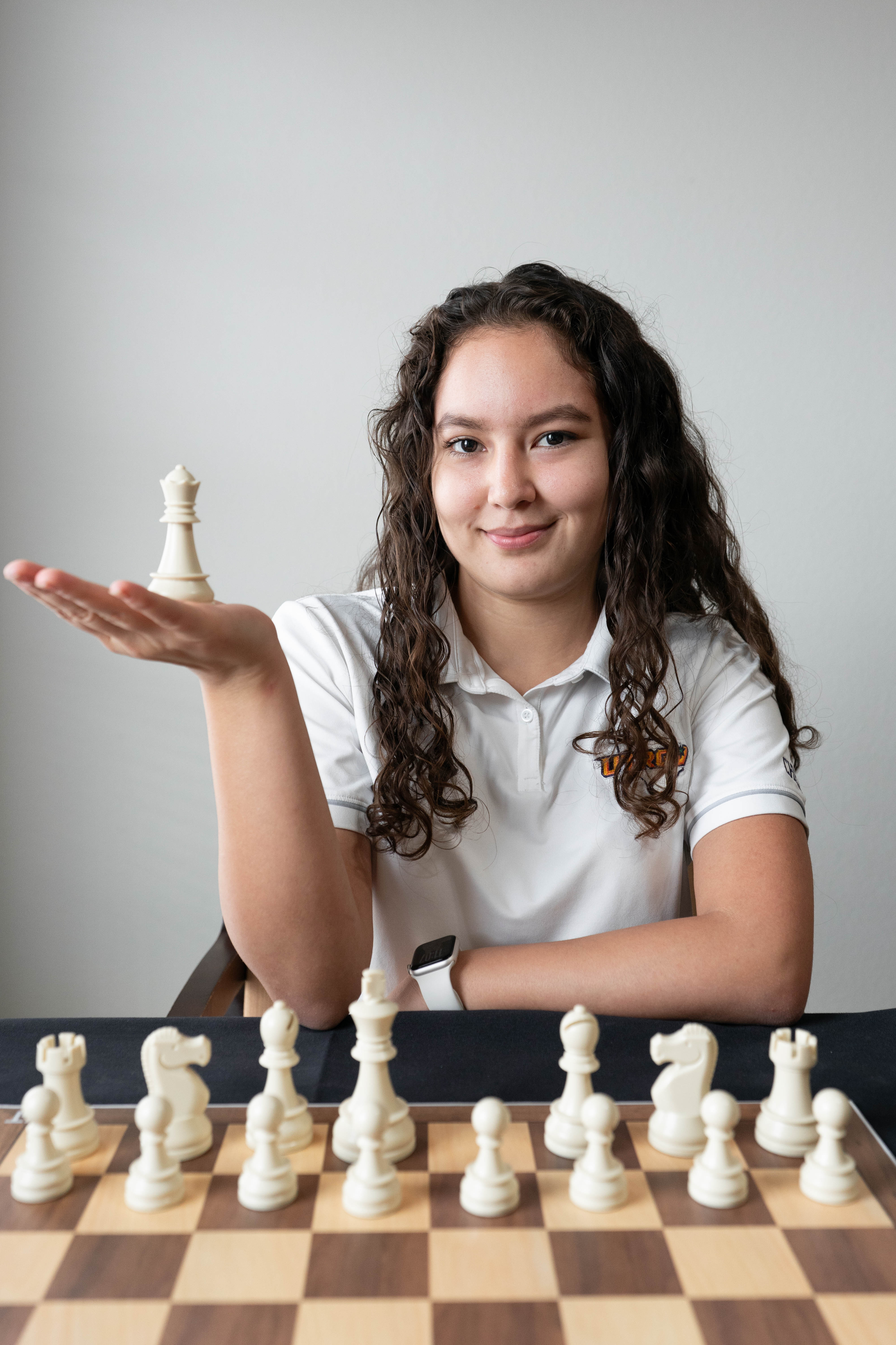 Woman holding a chess piece wearing a white polo shirt