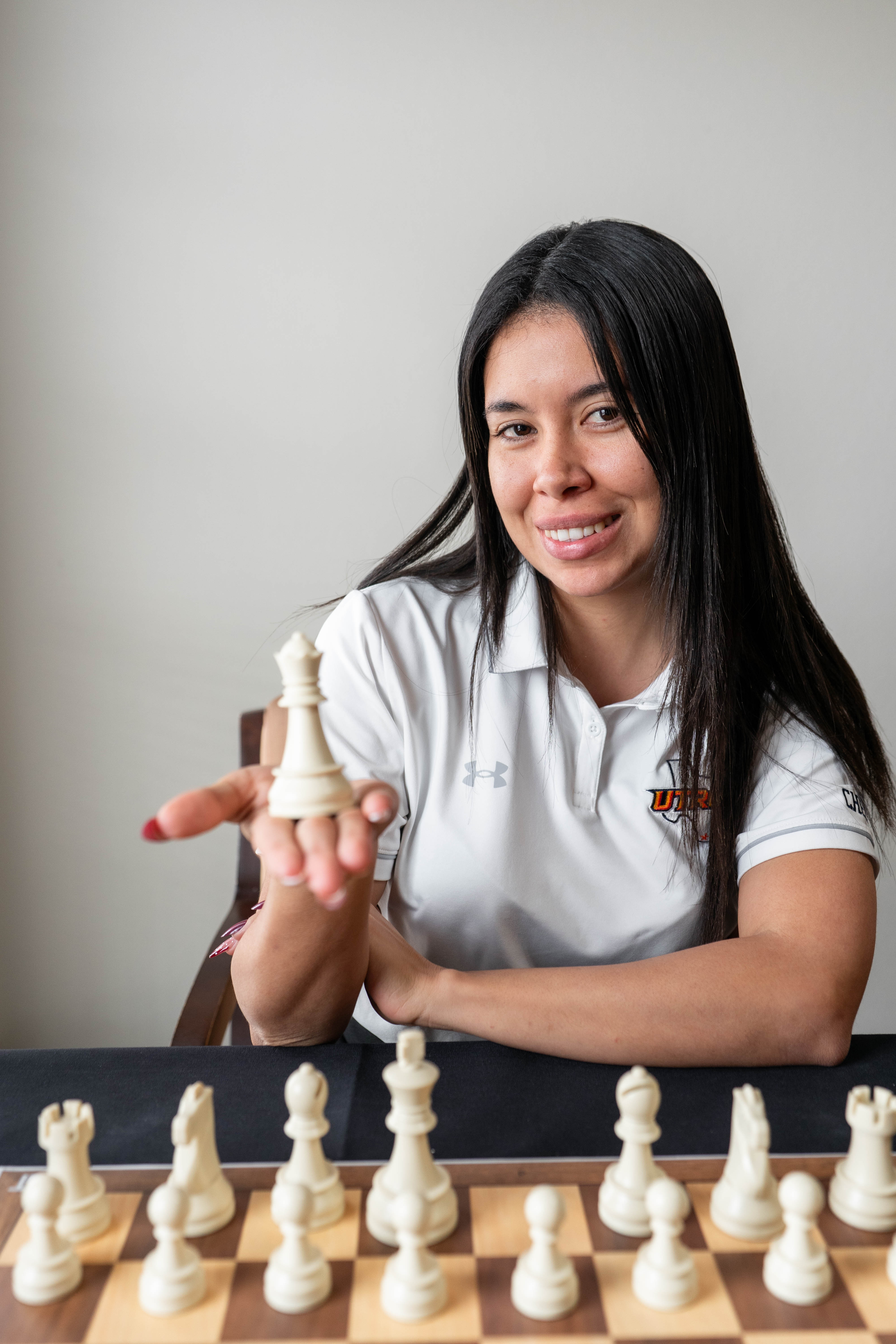 Woman holding up a chess piece wearing a white polo shirt
