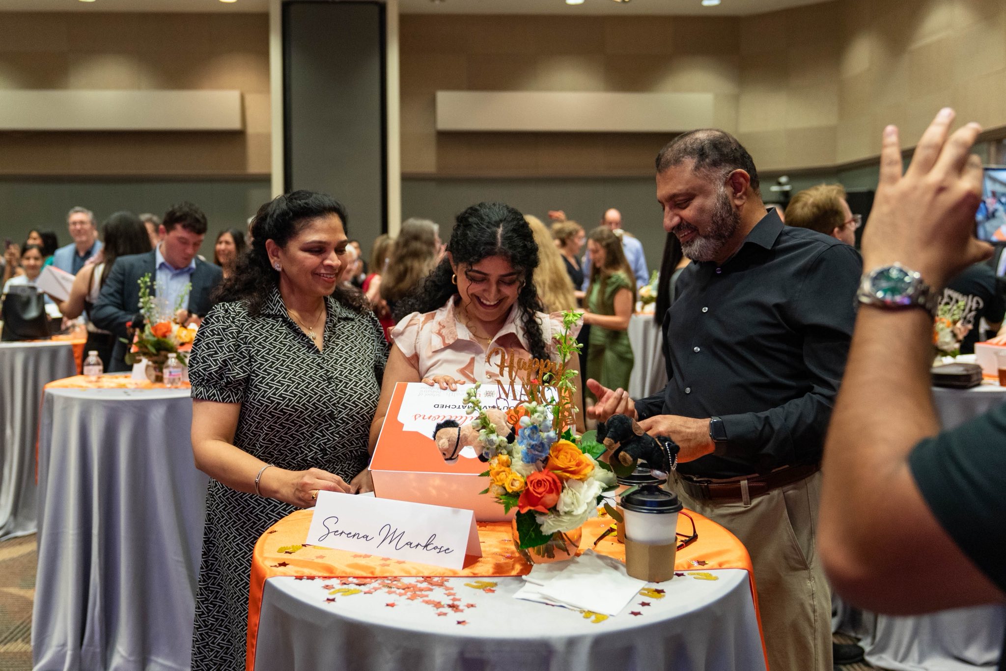 Three adults standing together as one opens a box