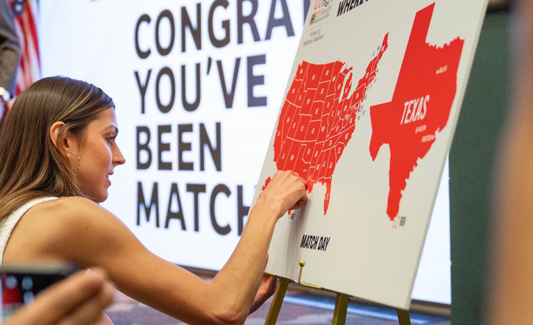 Woman stands in front of a map of the United States, placing a pin on the board