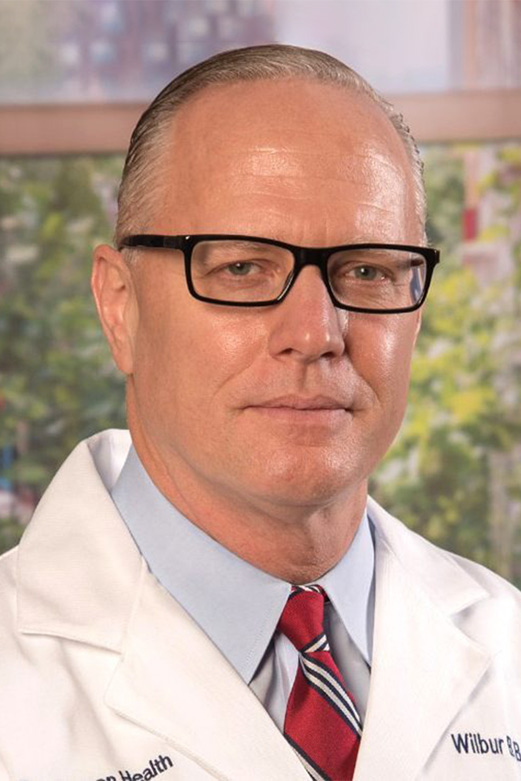 Man wearing a white coat and dark-framed classes